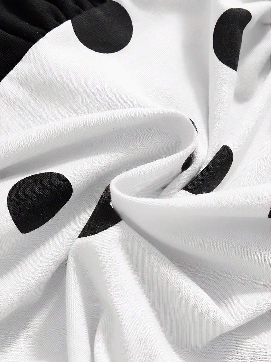 Black and white polka dot halter neck tank top featuring a backless design with ruched knot details and daisy accent.