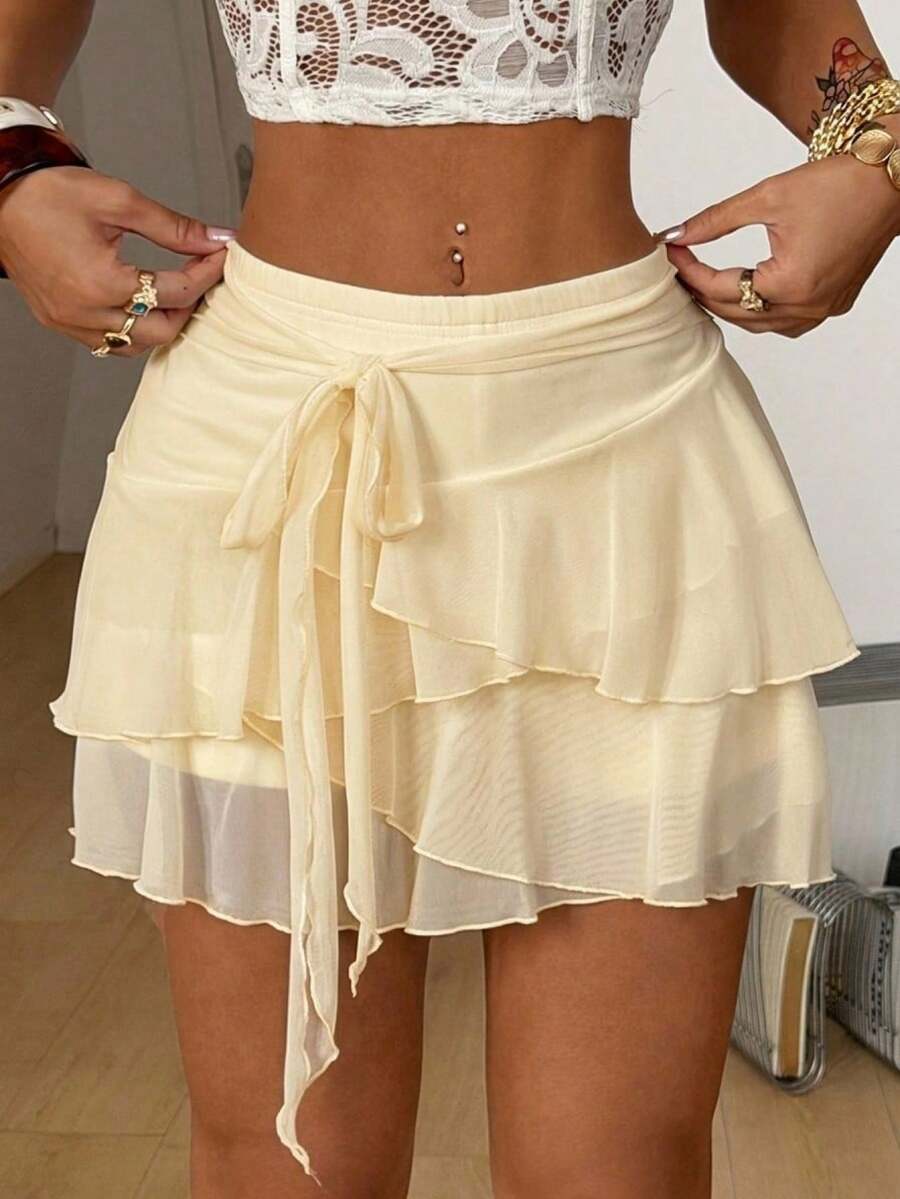 Black low waist tiered mini skirt featuring a ruffle hem and ring accent detail on knitted stretch fabric for women.