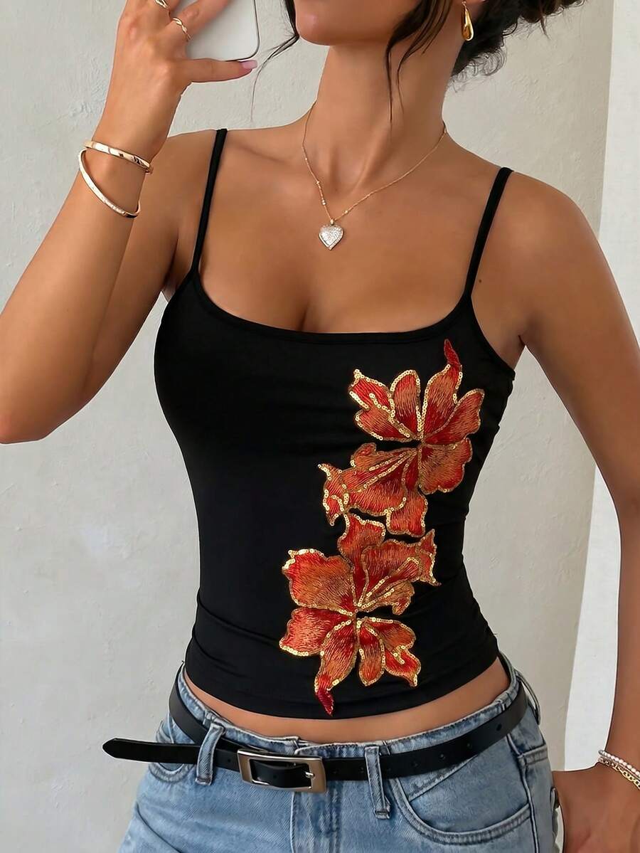 Women's black floral backless camisole top featuring spaghetti straps and front ring detail on knitted stretch fabric.