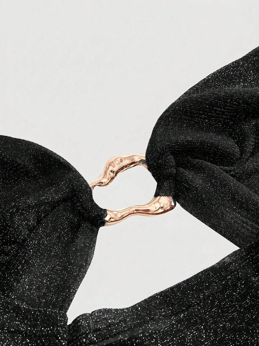 Women's glitter backless halter crop top with a draped neck and tie-up straps in metallic black knit fabric.