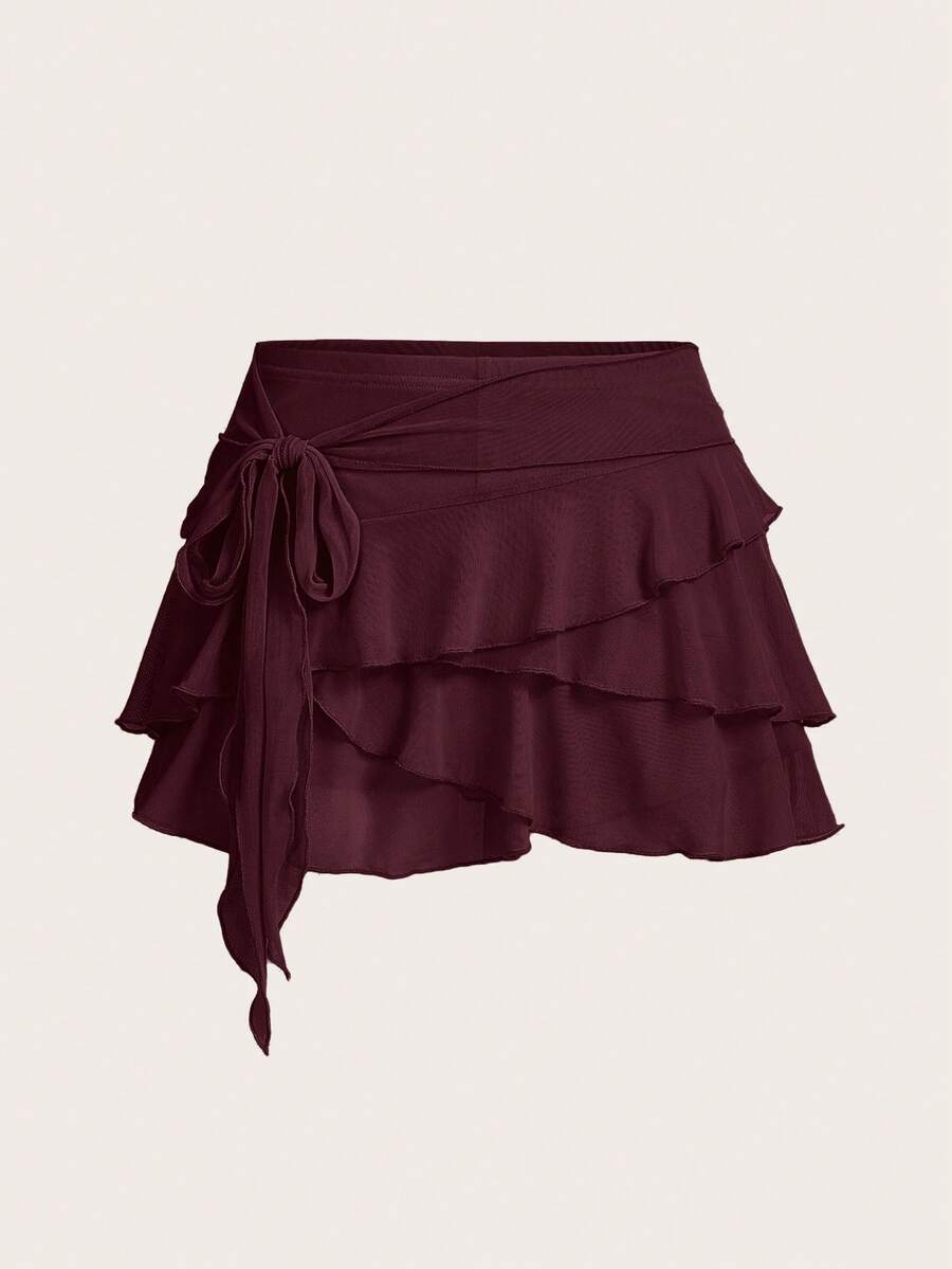 White tiered ruffle trim mini skirt for women with low waist, knot detail, mesh fabric, and casual Y2K boho design.