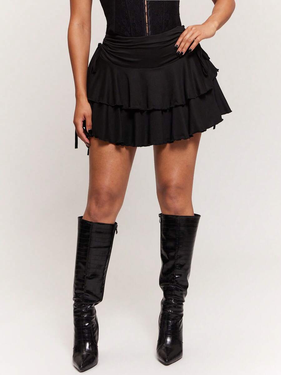 Women's black PU coated layered ruffle mini skirt featuring a high waist, tiered ruffle hem, and zipper detail.