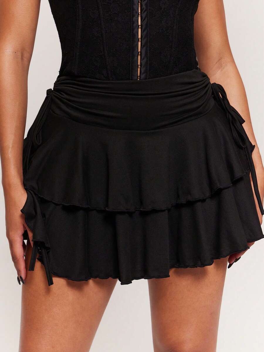 Women's black PU coated layered ruffle mini skirt featuring a high waist, tiered ruffle hem, and zipper detail.
