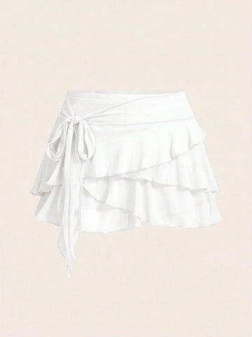 White tiered ruffle trim mini skirt for women with low waist, knot detail, mesh fabric, and casual Y2K boho design.