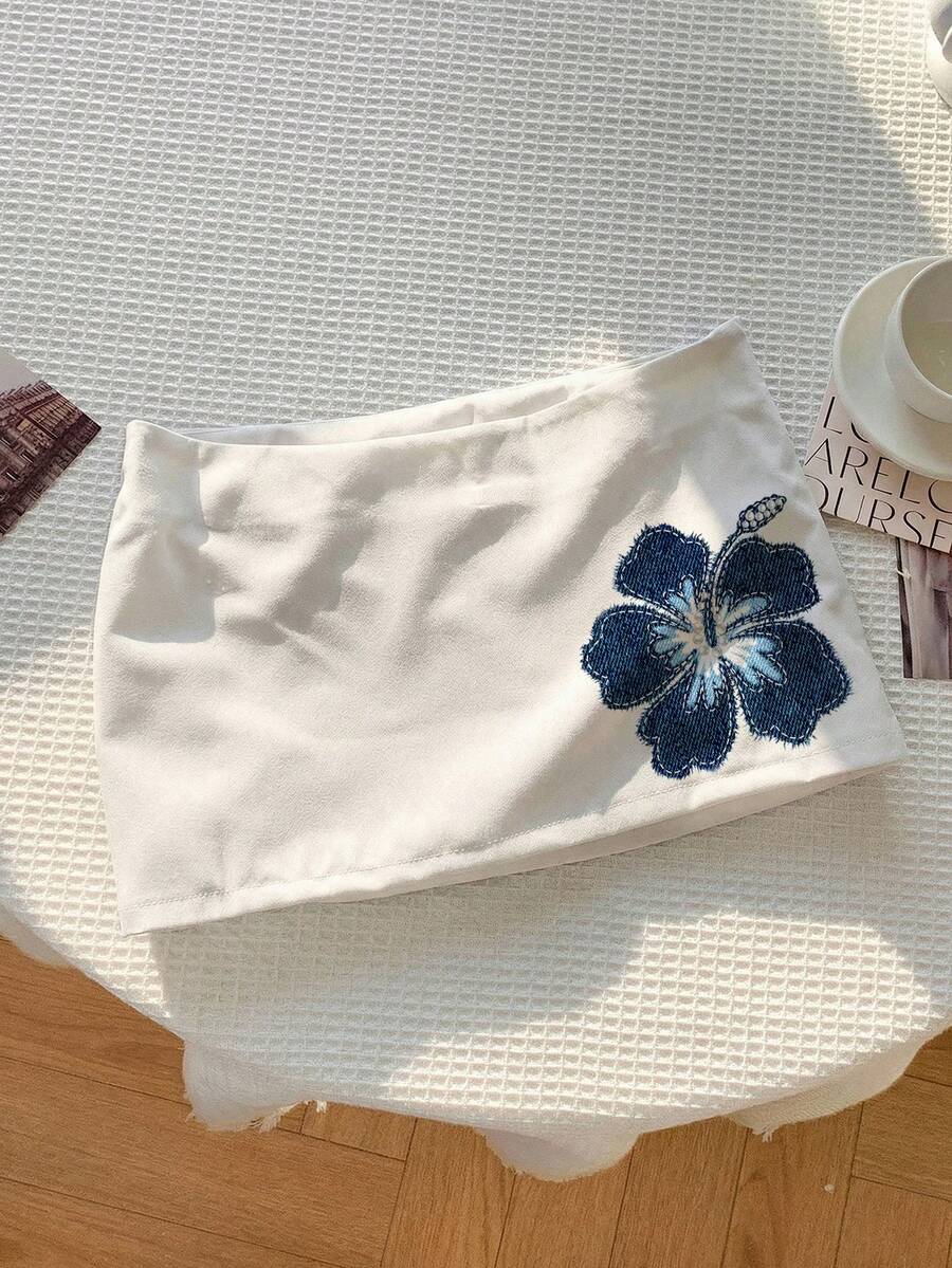 Women's white 100% cotton low waist mini skirt featuring a tropical print and zipper detail.