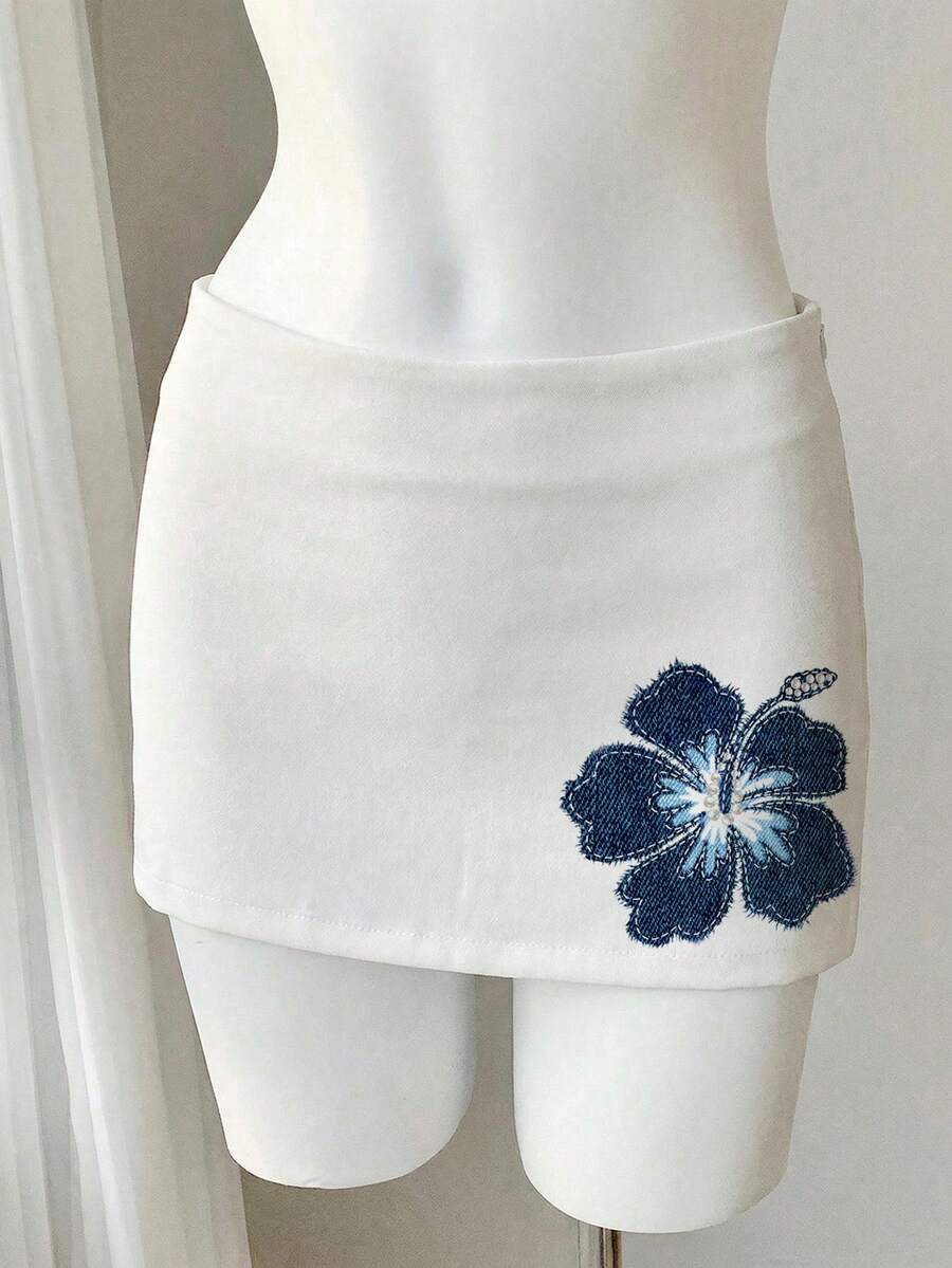 Women's white 100% cotton low waist mini skirt featuring a tropical print and zipper detail.