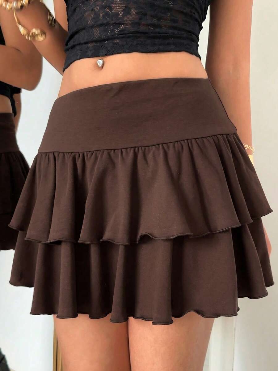 Black low waist knit mini skirt featuring a tiered ruffle hem and skinny high stretch fit.