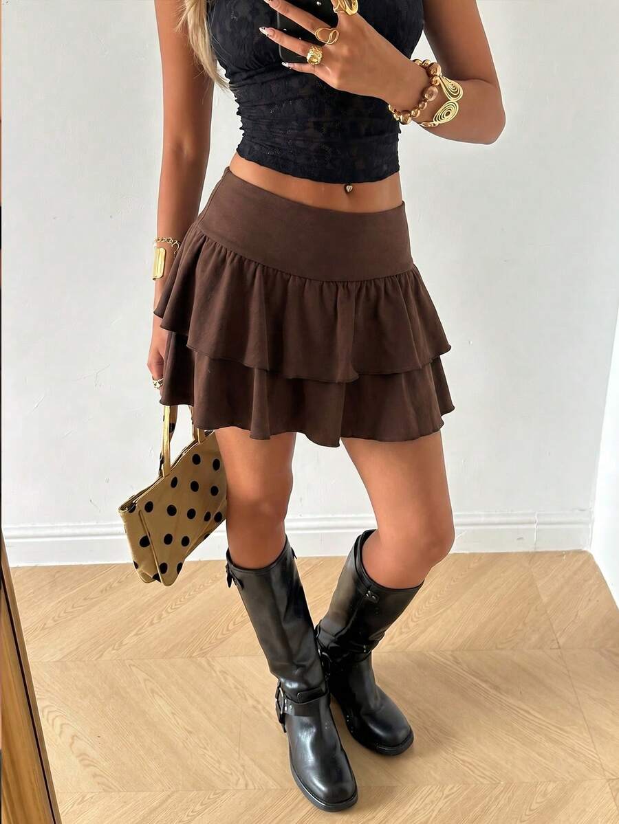 Black low waist knit mini skirt featuring a tiered ruffle hem and skinny high stretch fit.