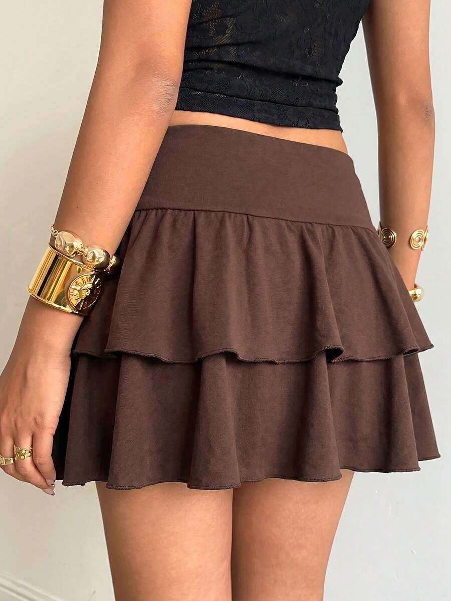 Black low waist knit mini skirt featuring a tiered ruffle hem and skinny high stretch fit.