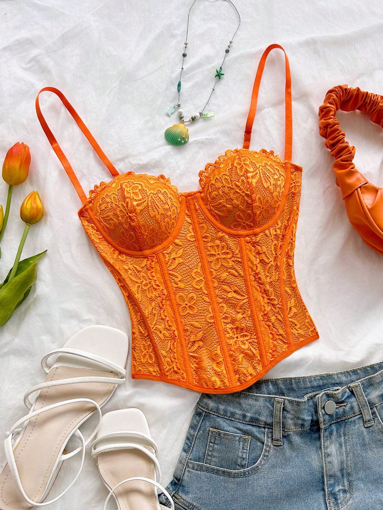 Women's lace bustier camisole top with spaghetti straps, contrast lace, lace-up detail, and an asymmetrical hem in a slim fit design.