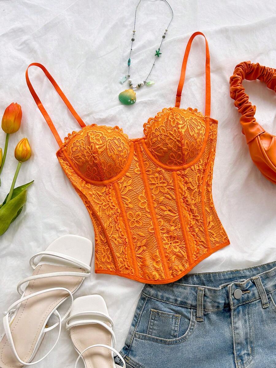 Women's lace bustier camisole top with spaghetti straps, contrast lace, lace-up detail, and an asymmetrical hem in a slim fit design.