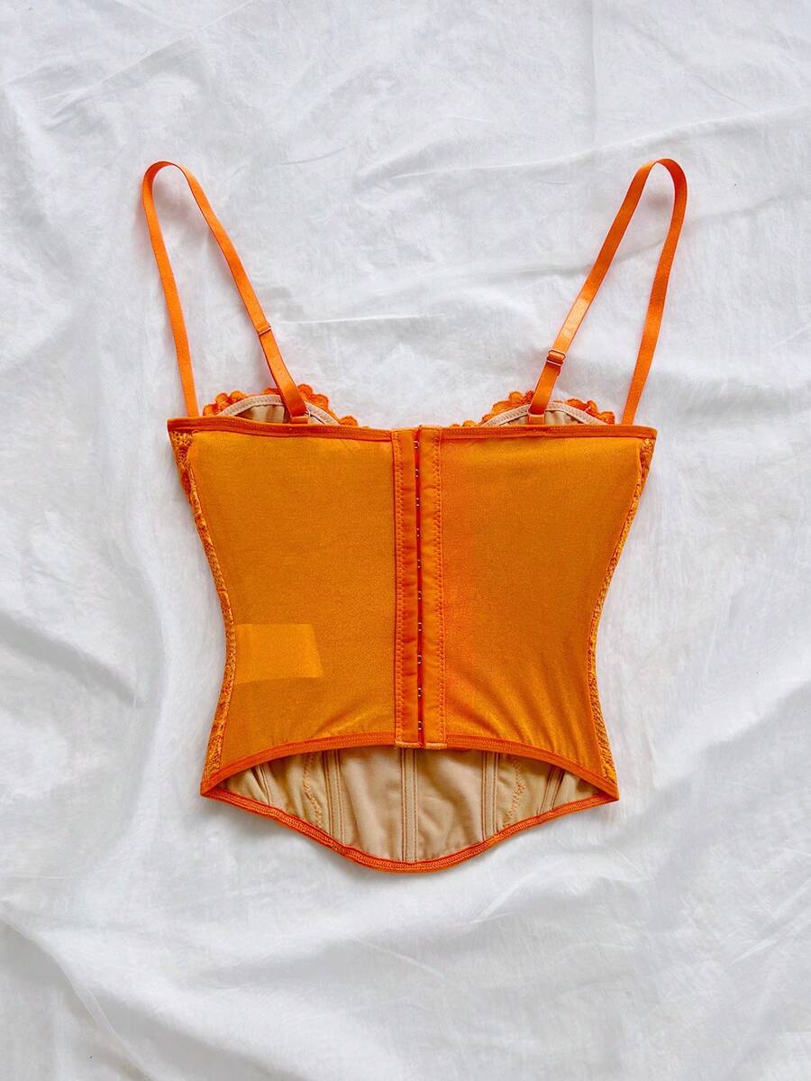 Women's lace bustier camisole top with spaghetti straps, contrast lace, lace-up detail, and an asymmetrical hem in a slim fit design.
