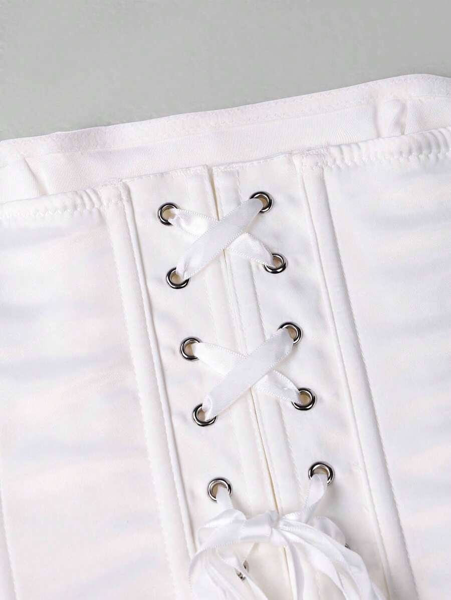 White strapless satin corset crop top for women featuring internal boning, a lace-up backless detail, and an asymmetrical hem.