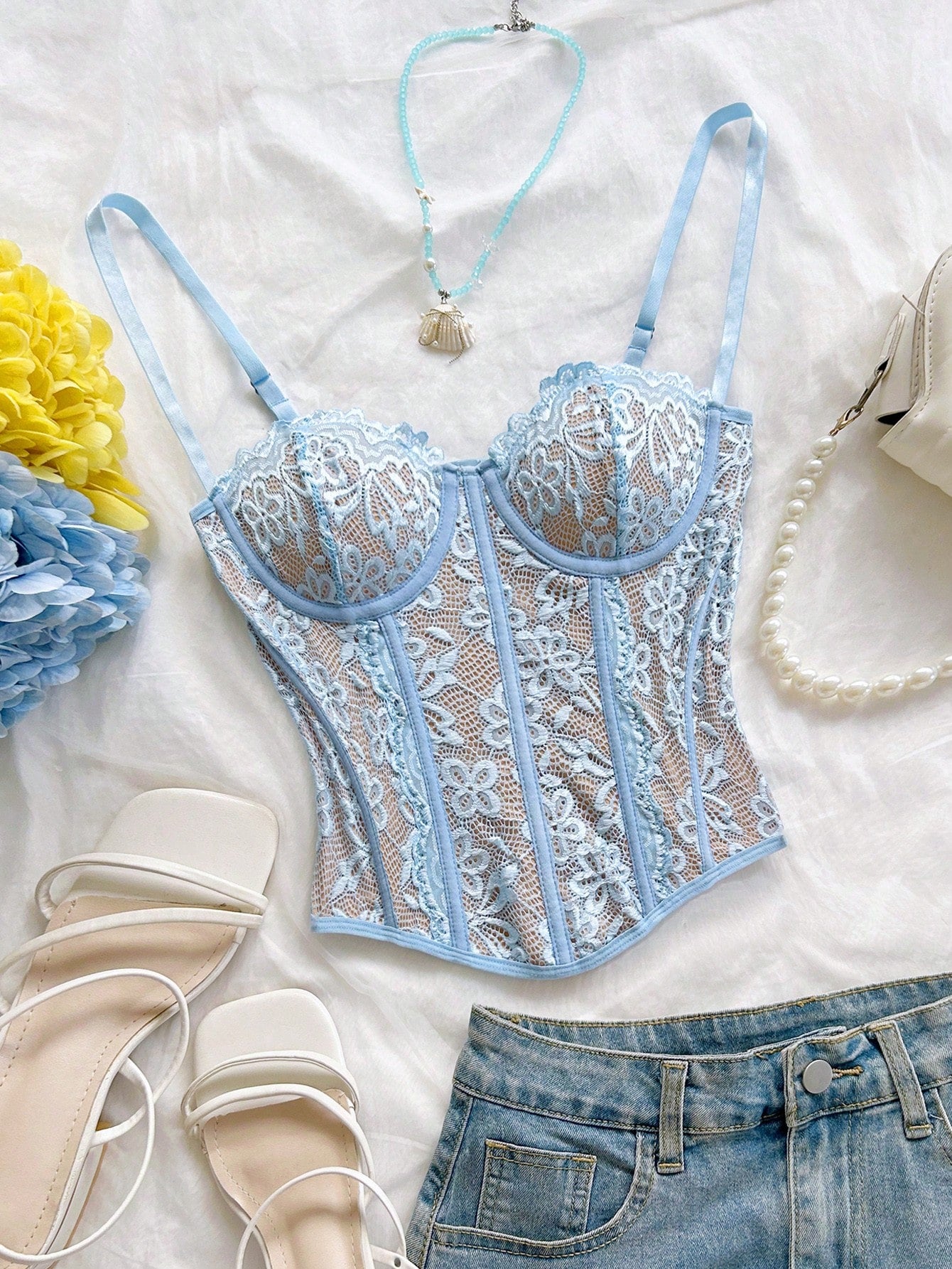 Women's lace bustier camisole top with spaghetti straps, contrast lace, lace-up detail, and an asymmetrical hem in a slim fit design.