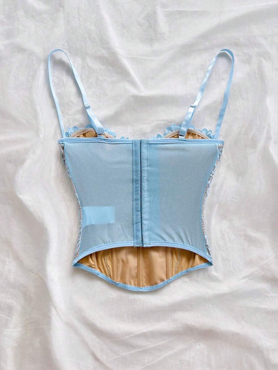 Women's lace bustier camisole top with spaghetti straps, contrast lace, lace-up detail, and an asymmetrical hem in a slim fit design.