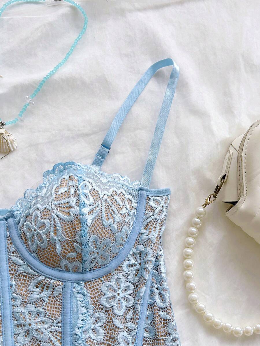 Women's lace bustier camisole top with spaghetti straps, contrast lace, lace-up detail, and an asymmetrical hem in a slim fit design.