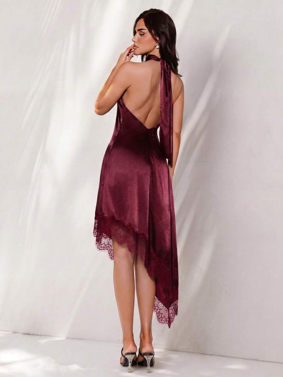 Black halter neck mini dress for women featuring a backless design with a large bow detail and an asymmetric contrast lace hem.