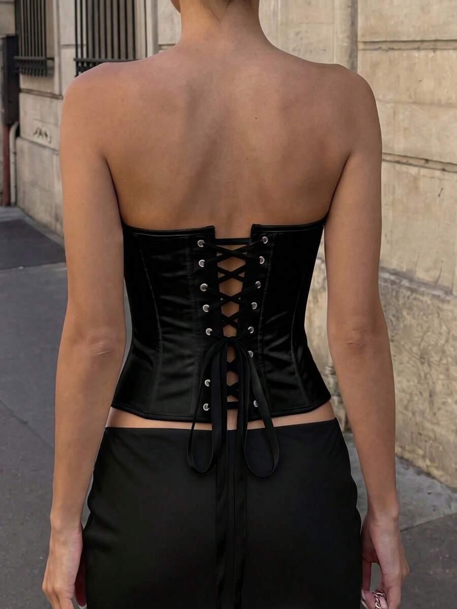 White women’s corset top with metal eyelet details, boning structure, spaghetti straps, backless tie-back design, and a slim cropped fit.