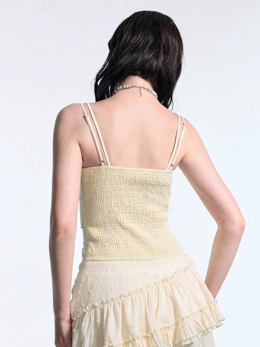 White lace-up crop camisole top for women featuring grommet eyelet details, a sweetheart neckline, shirred back, and asymmetrical hem.