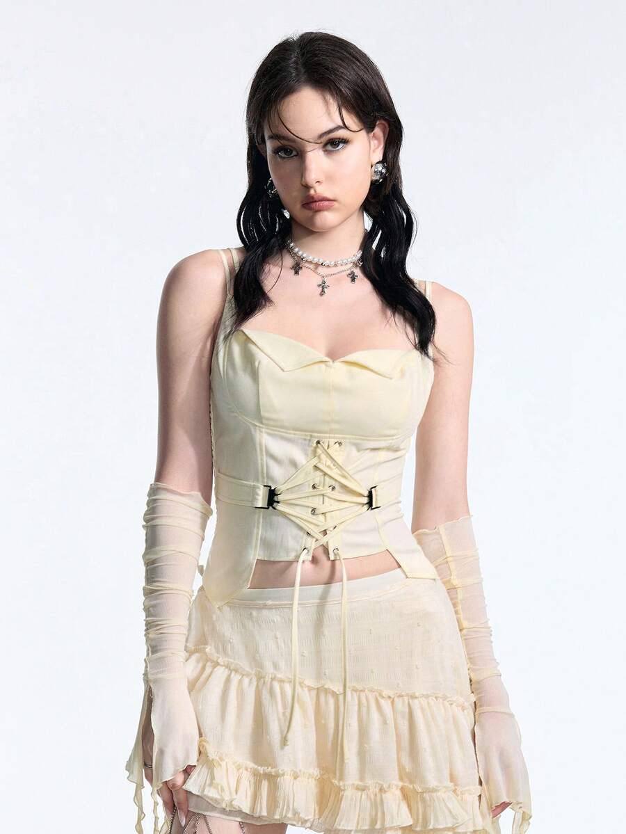 White lace-up crop camisole top for women featuring grommet eyelet details, a sweetheart neckline, shirred back, and asymmetrical hem.