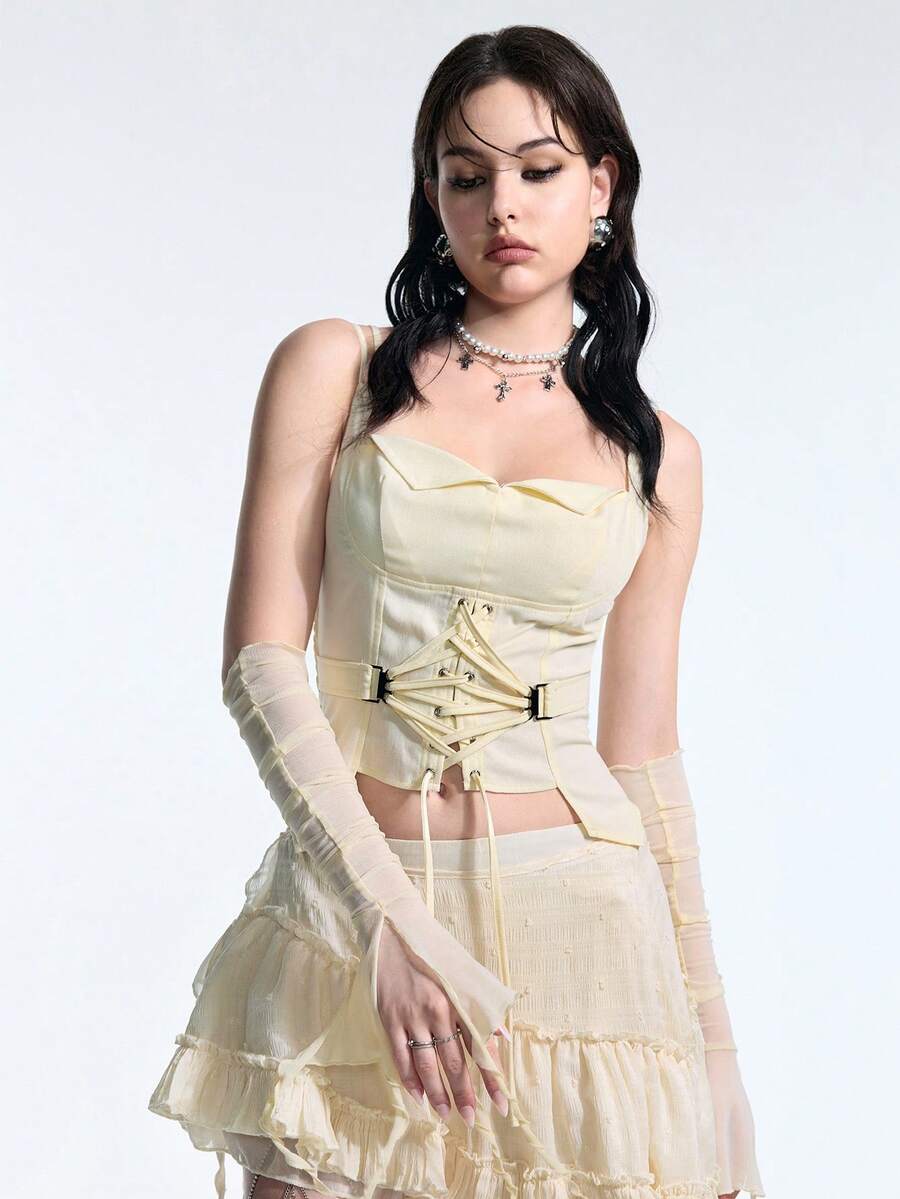 White lace-up crop camisole top for women featuring grommet eyelet details, a sweetheart neckline, shirred back, and asymmetrical hem.