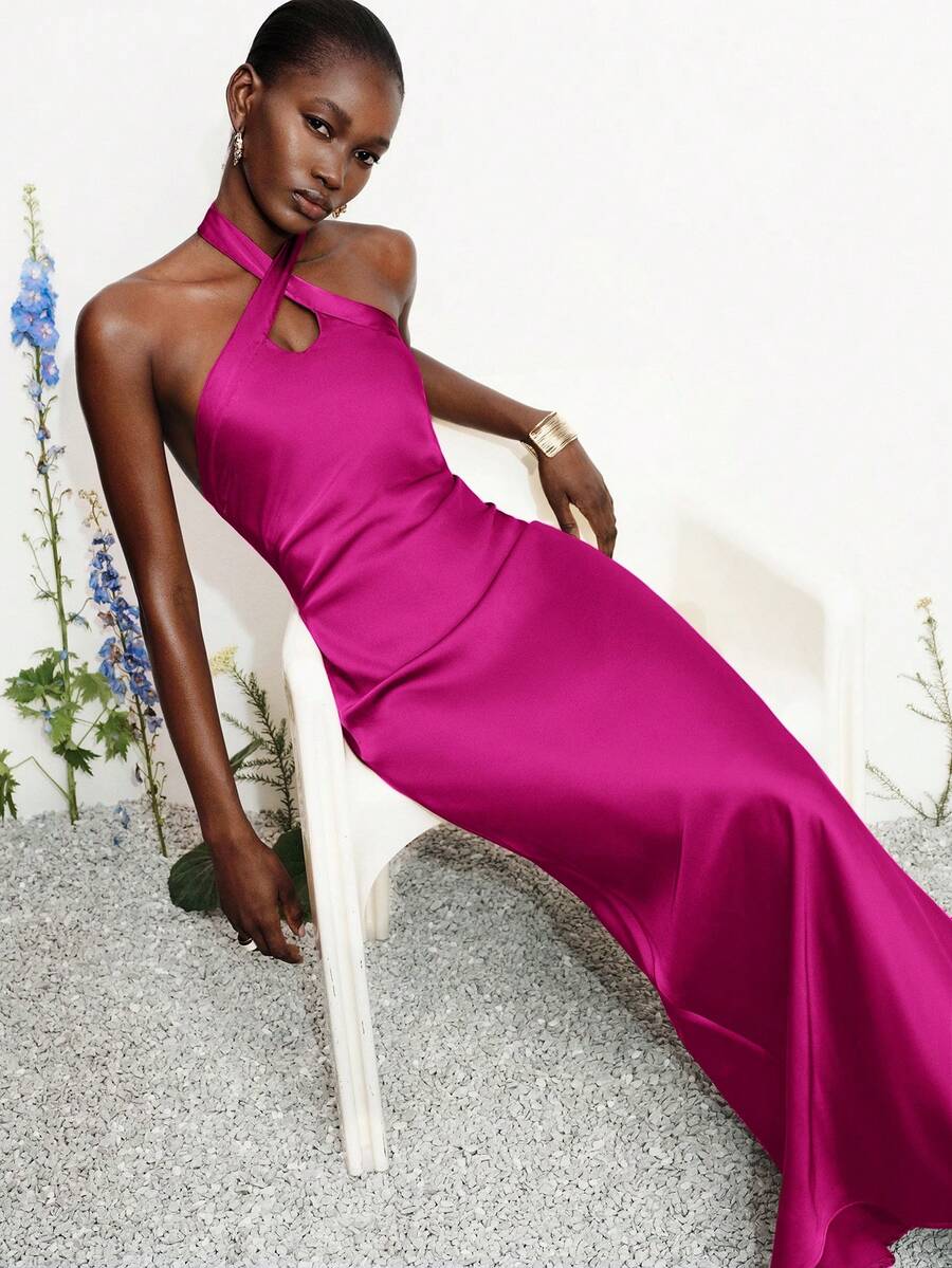 Women's black satin halter neck bodycon midi dress featuring a sleeveless backless design with front slit hem and wrap details.