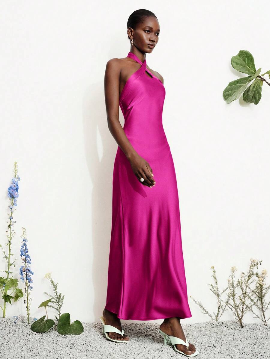 Women's black satin halter neck bodycon midi dress featuring a sleeveless backless design with front slit hem and wrap details.