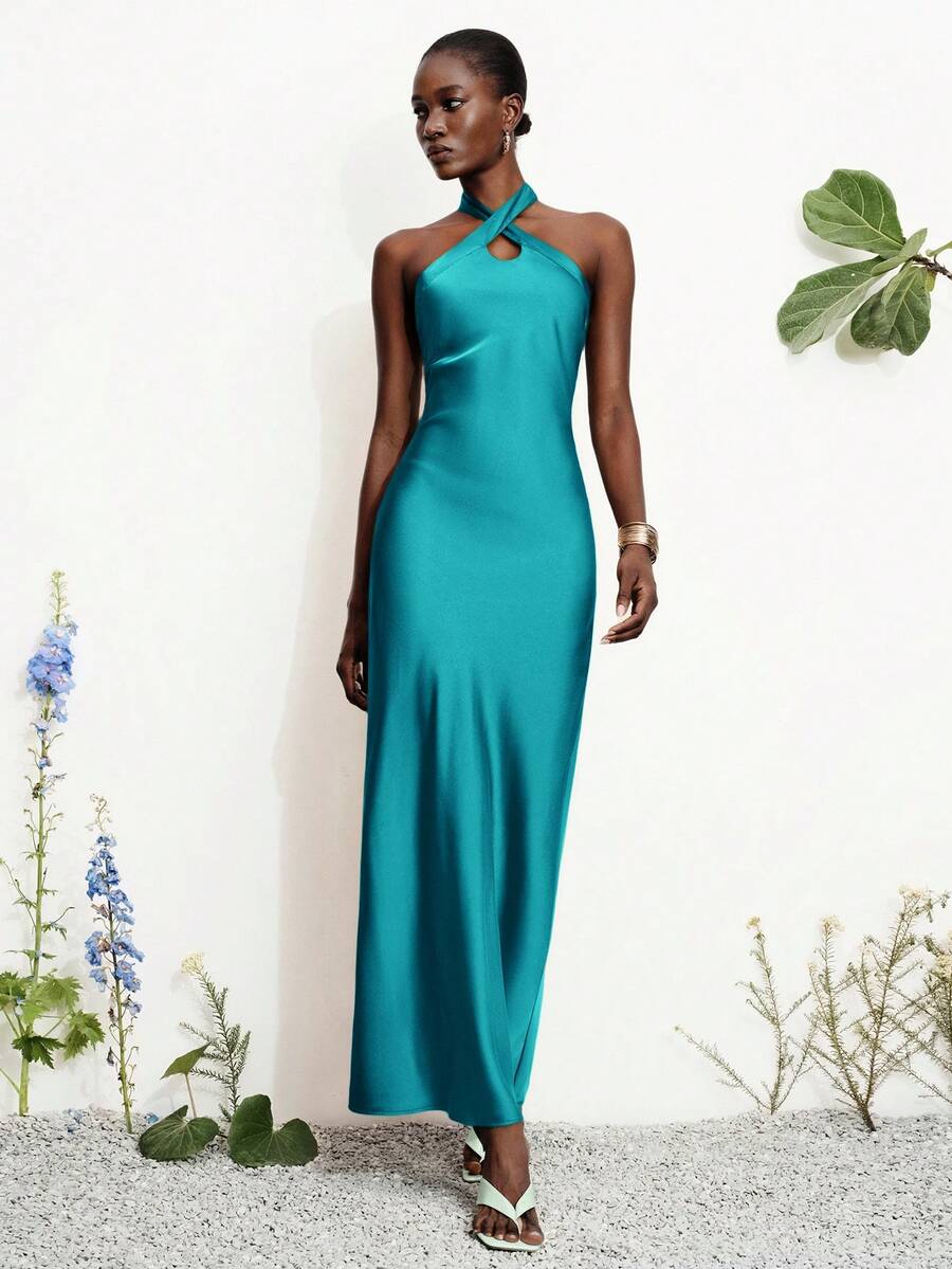 Women's black satin halter neck bodycon midi dress featuring a sleeveless backless design with front slit hem and wrap details.