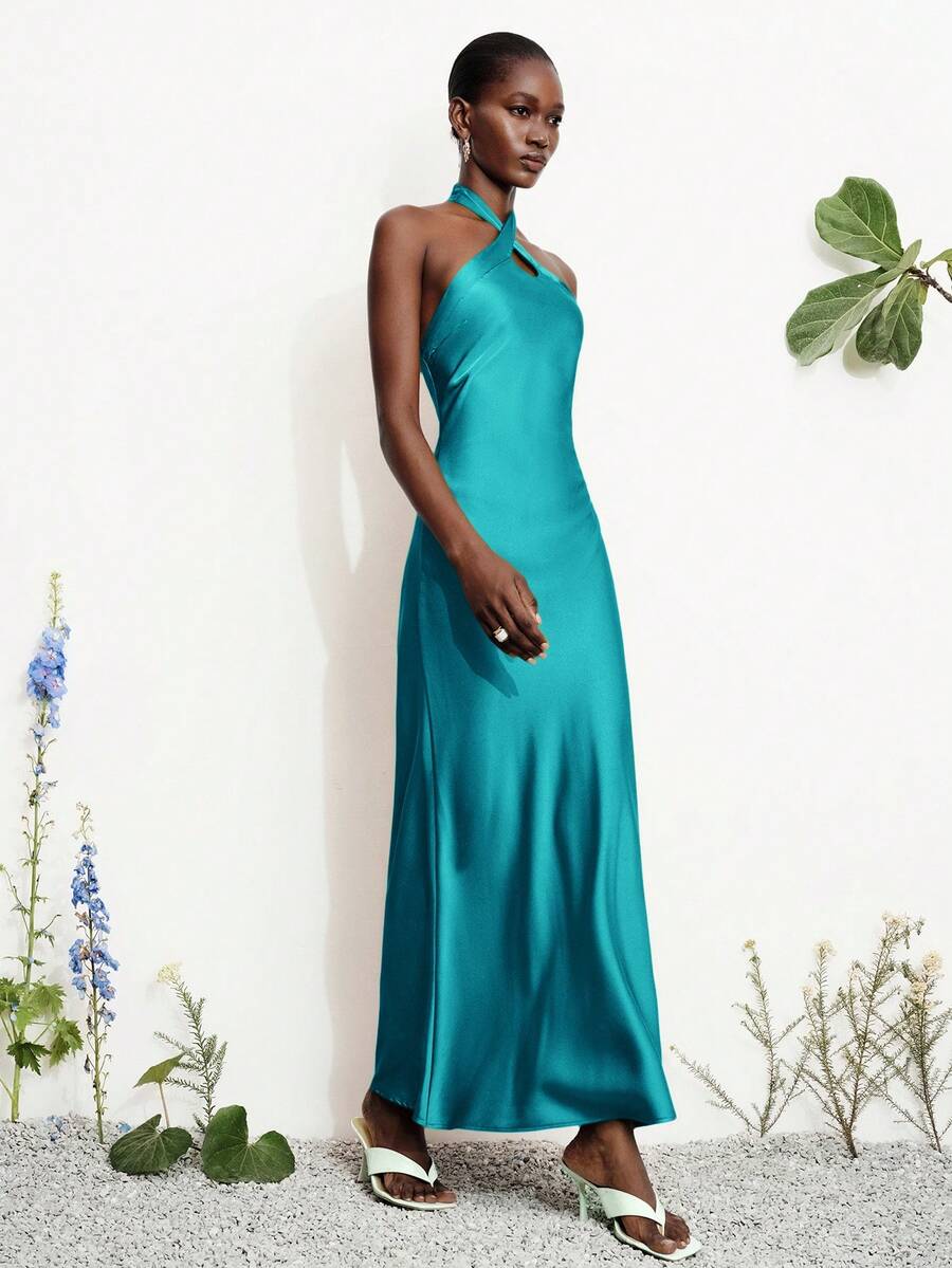 Women's black satin halter neck bodycon midi dress featuring a sleeveless backless design with front slit hem and wrap details.