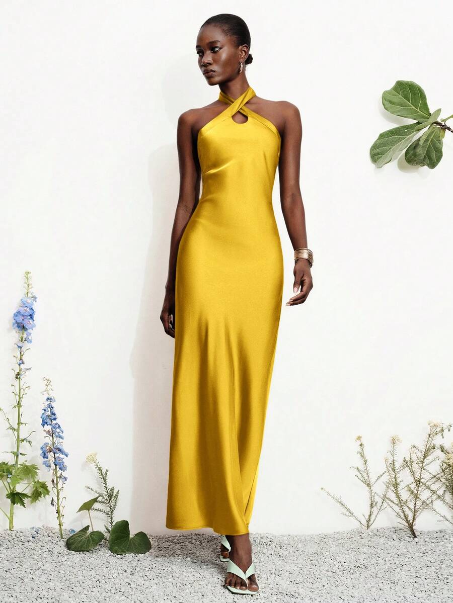 Women's black satin halter neck bodycon midi dress featuring a sleeveless backless design with front slit hem and wrap details.