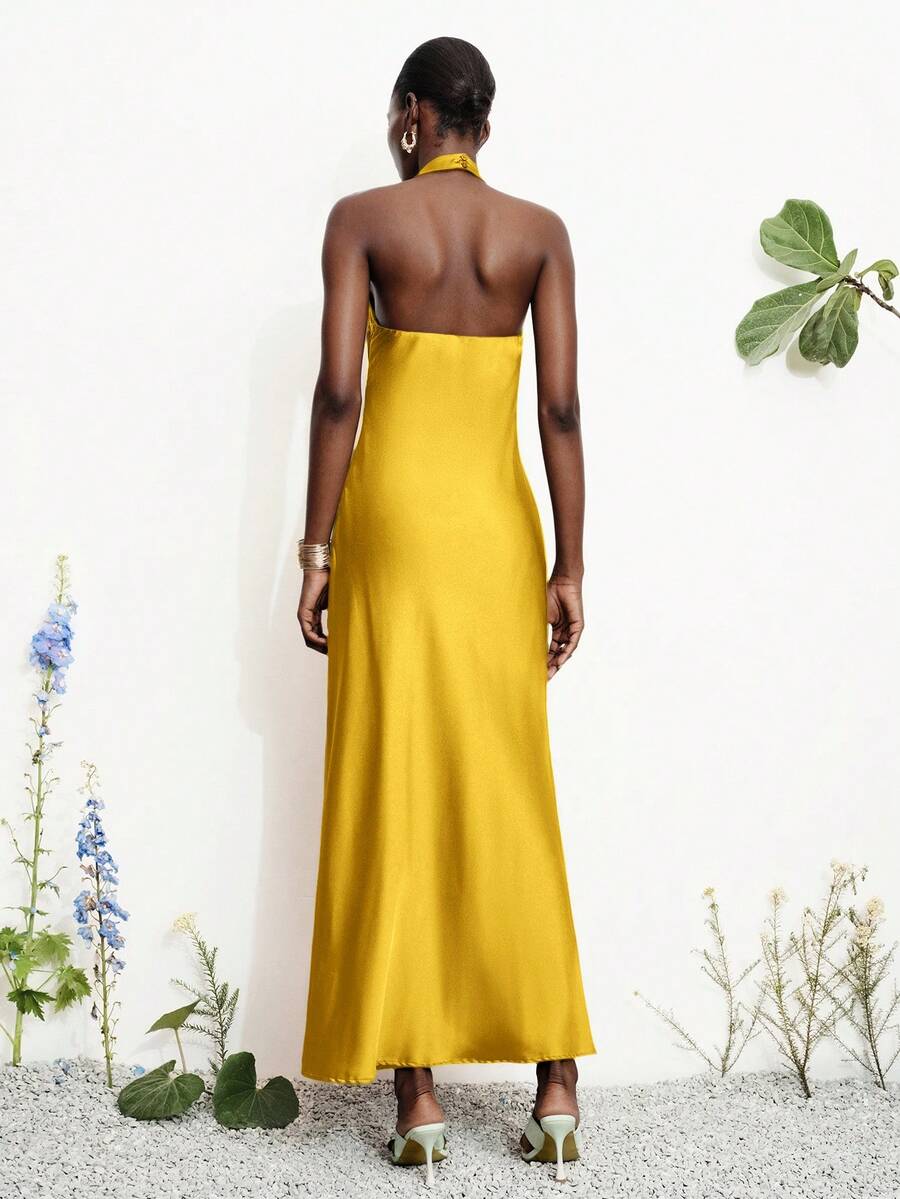 Women's black satin halter neck bodycon midi dress featuring a sleeveless backless design with front slit hem and wrap details.