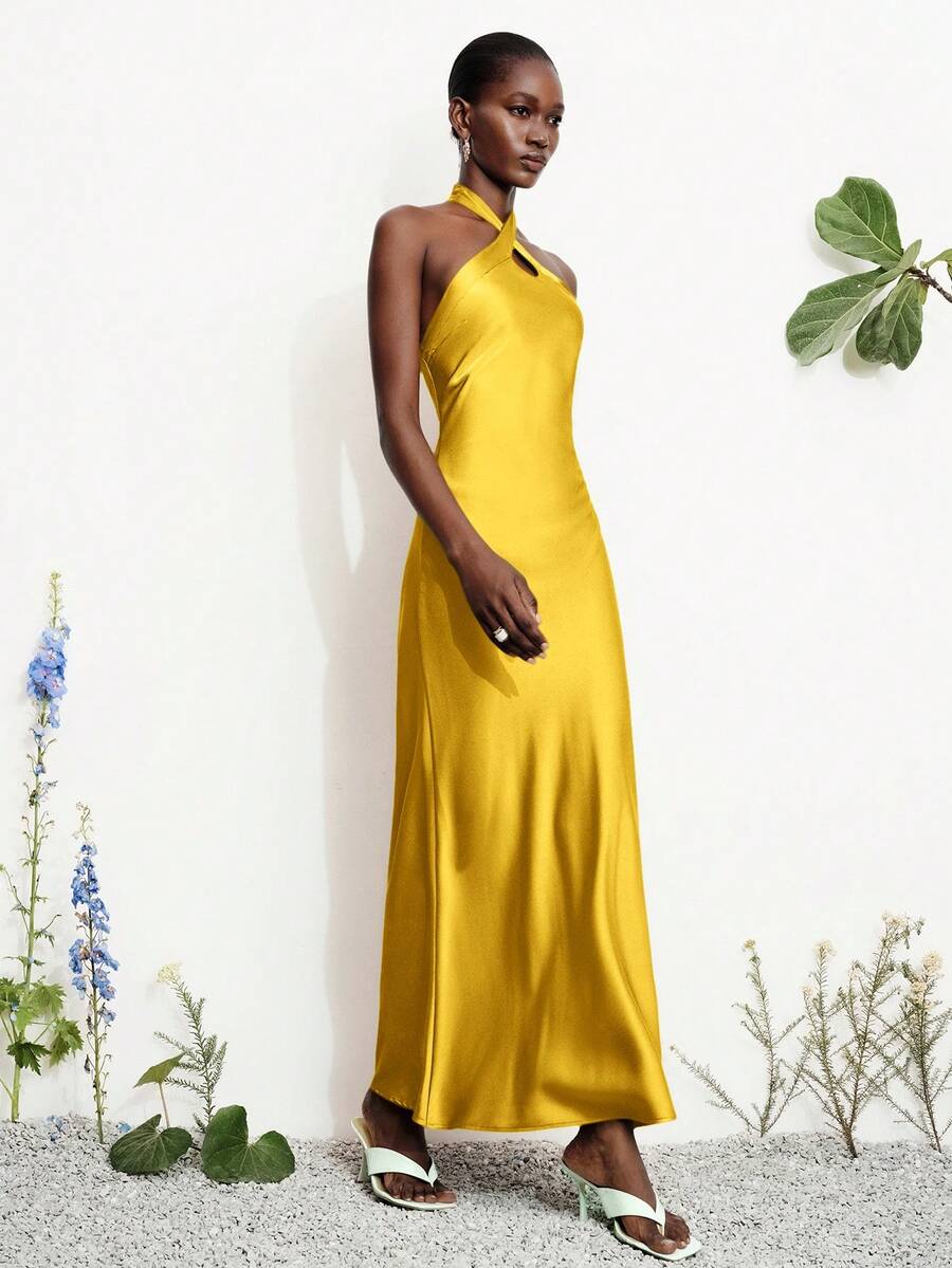 Women's black satin halter neck bodycon midi dress featuring a sleeveless backless design with front slit hem and wrap details.