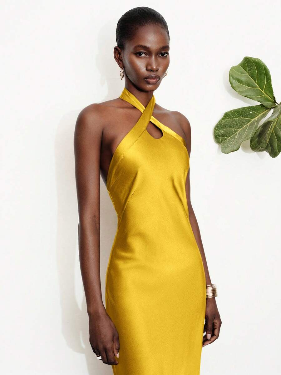 Women's black satin halter neck bodycon midi dress featuring a sleeveless backless design with front slit hem and wrap details.