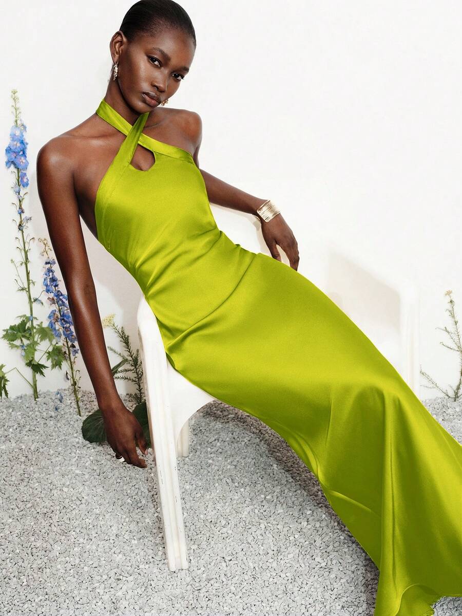 Women's black satin halter neck bodycon midi dress featuring a sleeveless backless design with front slit hem and wrap details.