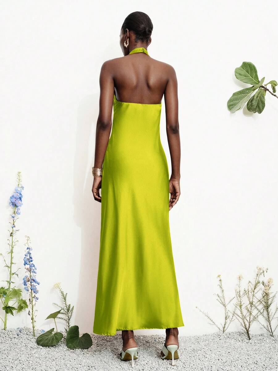Women's black satin halter neck bodycon midi dress featuring a sleeveless backless design with front slit hem and wrap details.