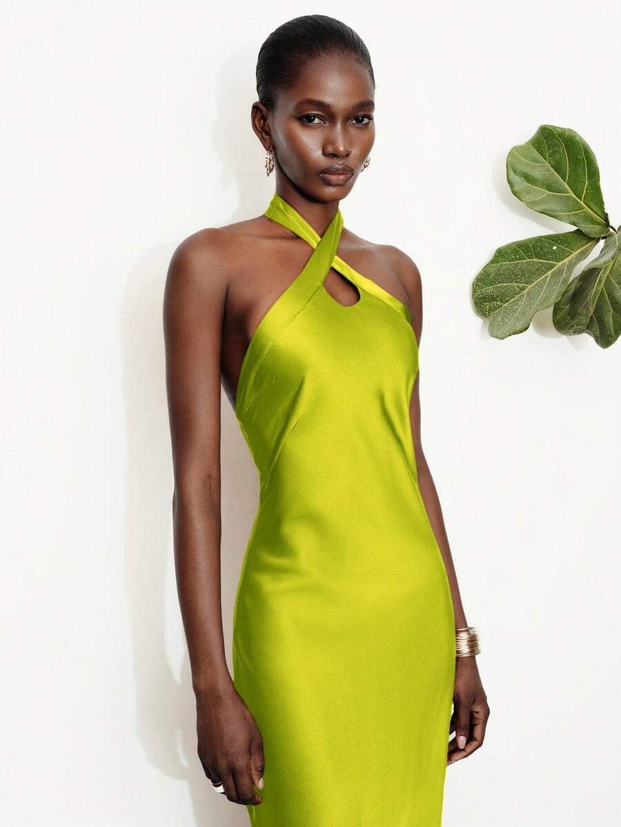 Women's black satin halter neck bodycon midi dress featuring a sleeveless backless design with front slit hem and wrap details.