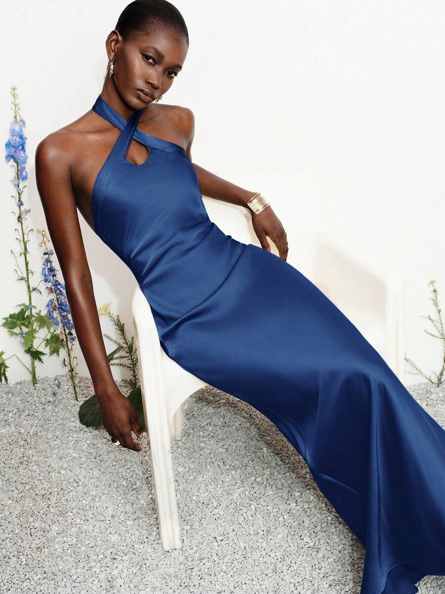 Women's black satin halter neck bodycon midi dress featuring a sleeveless backless design with front slit hem and wrap details.