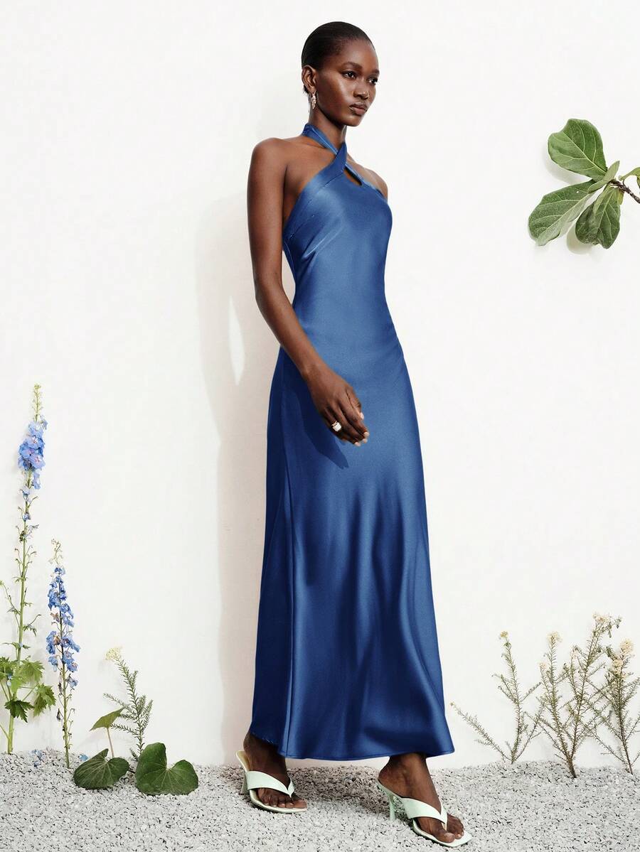 Women's black satin halter neck bodycon midi dress featuring a sleeveless backless design with front slit hem and wrap details.