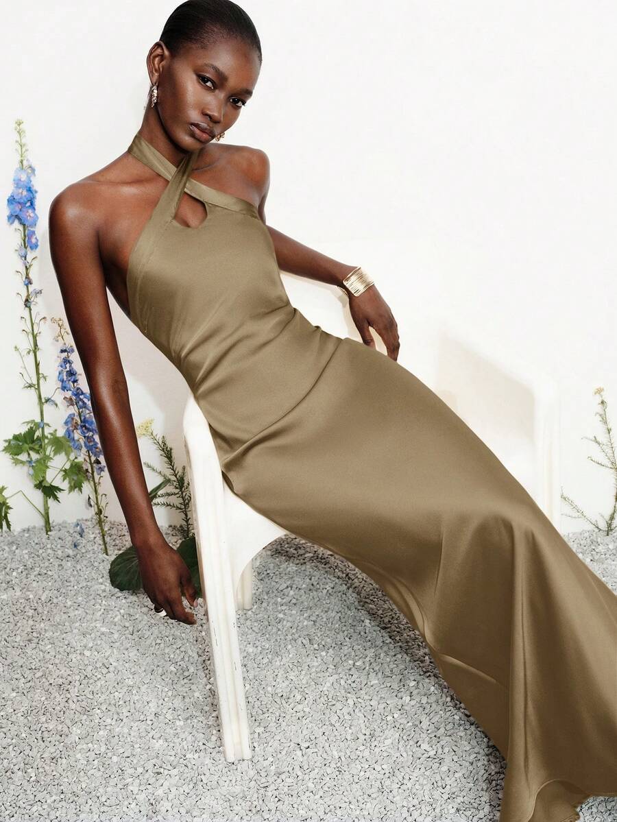 Women's black satin halter neck bodycon midi dress featuring a sleeveless backless design with front slit hem and wrap details.