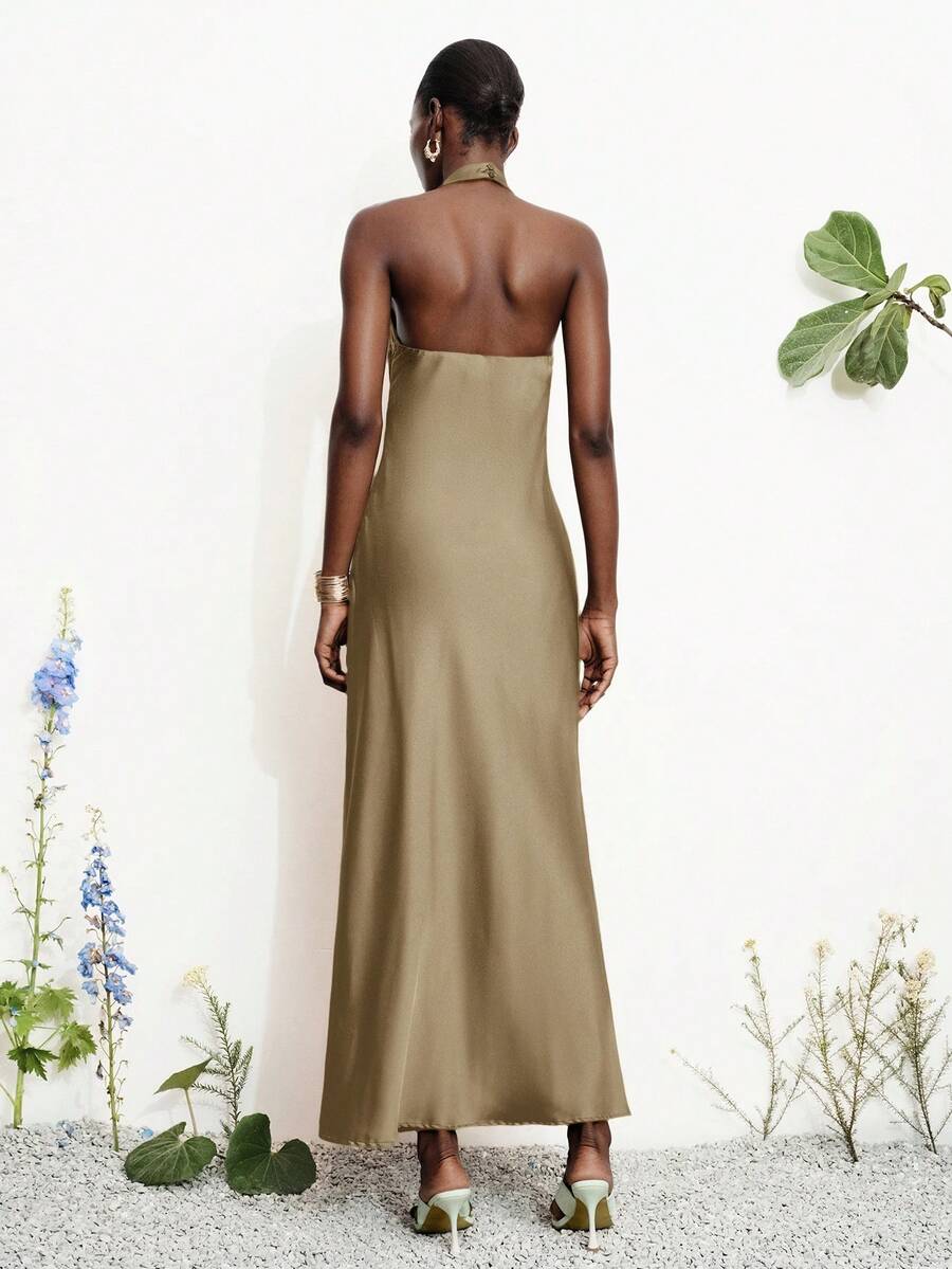 Women's black satin halter neck bodycon midi dress featuring a sleeveless backless design with front slit hem and wrap details.