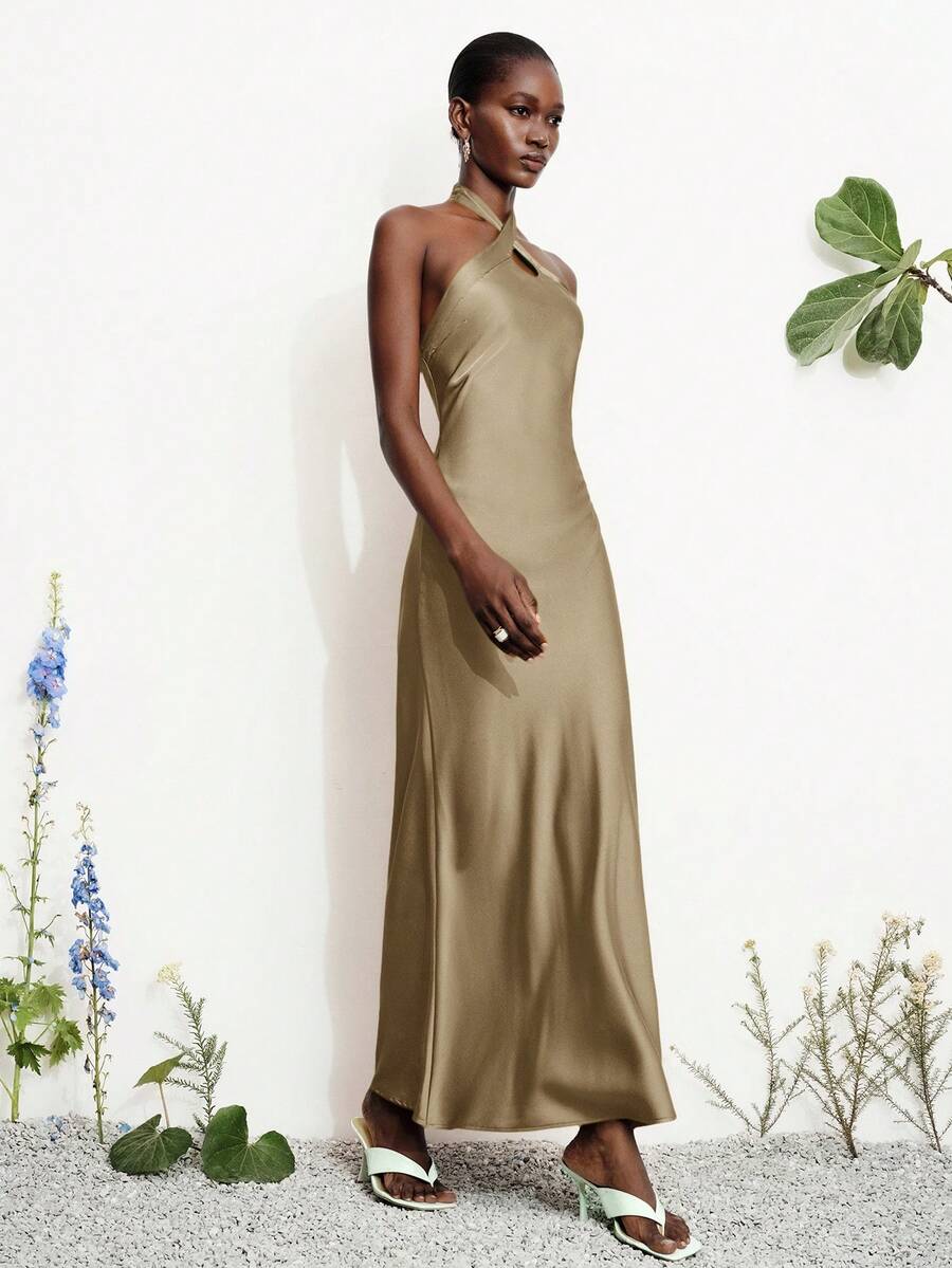 Women's black satin halter neck bodycon midi dress featuring a sleeveless backless design with front slit hem and wrap details.