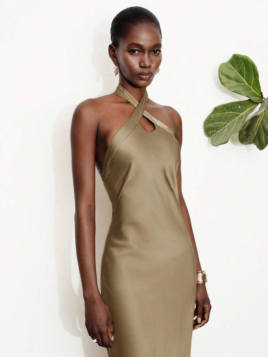 Women's black satin halter neck bodycon midi dress featuring a sleeveless backless design with front slit hem and wrap details.