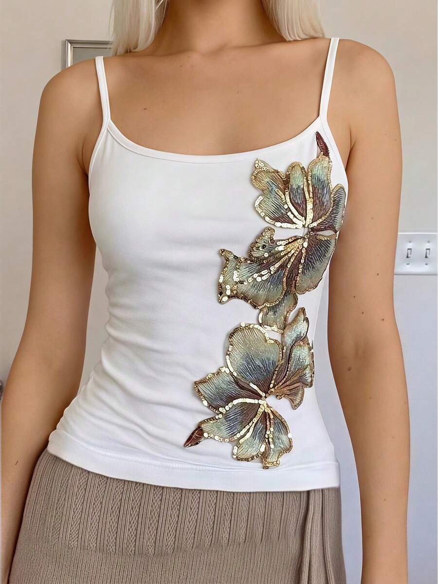Women's black floral backless camisole top featuring spaghetti straps and front ring detail on knitted stretch fabric.