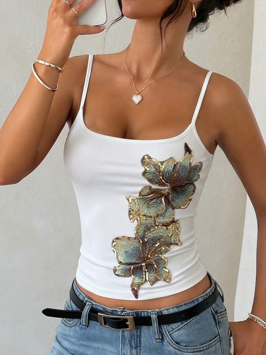 Women's black floral backless camisole top featuring spaghetti straps and front ring detail on knitted stretch fabric.