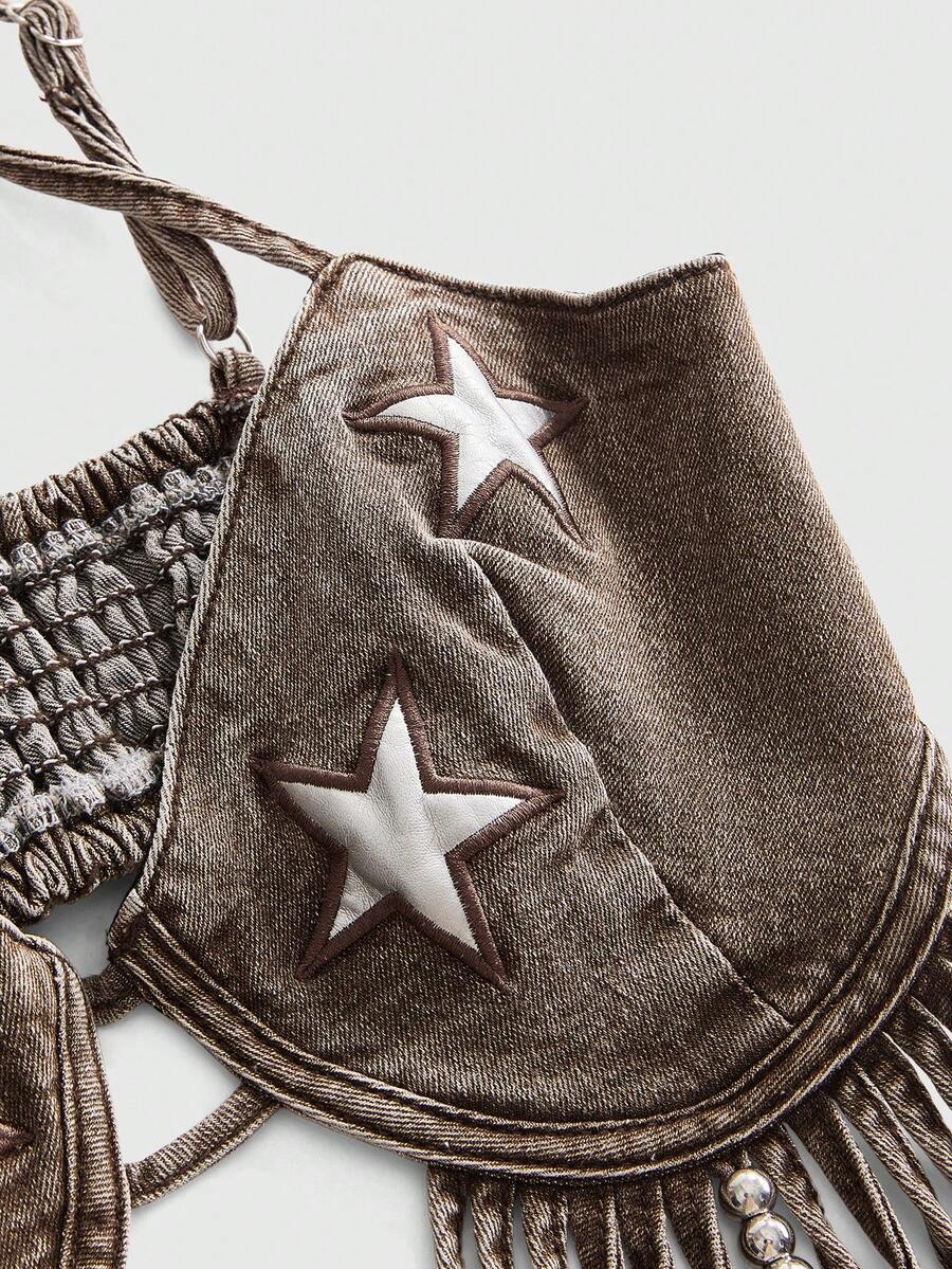 Blue denim camisole top for women featuring star patch detailing, fringe tassel asymmetrical hem, and spaghetti straps.