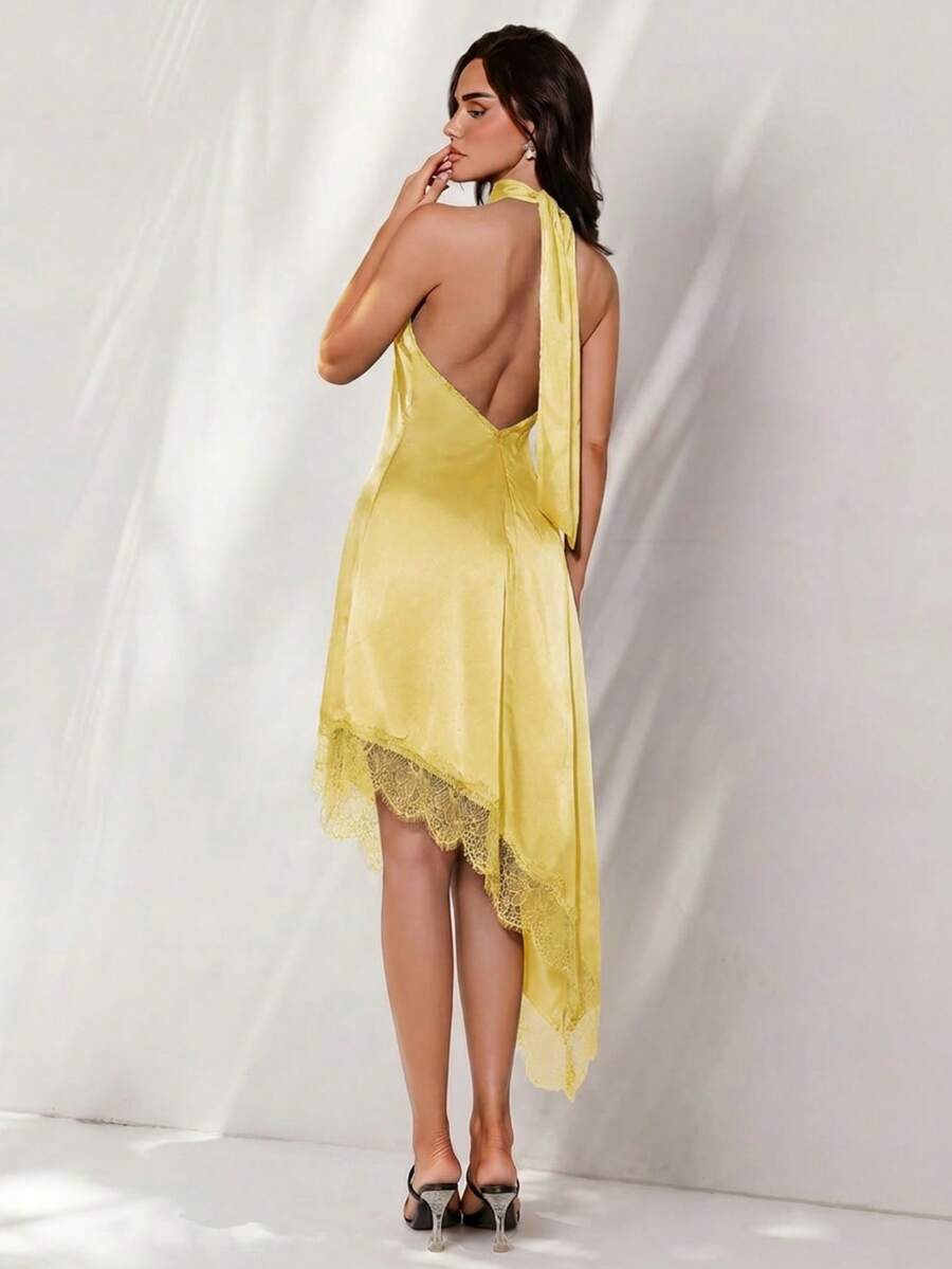 Black halter neck mini dress for women featuring a backless design with a large bow detail and an asymmetric contrast lace hem.
