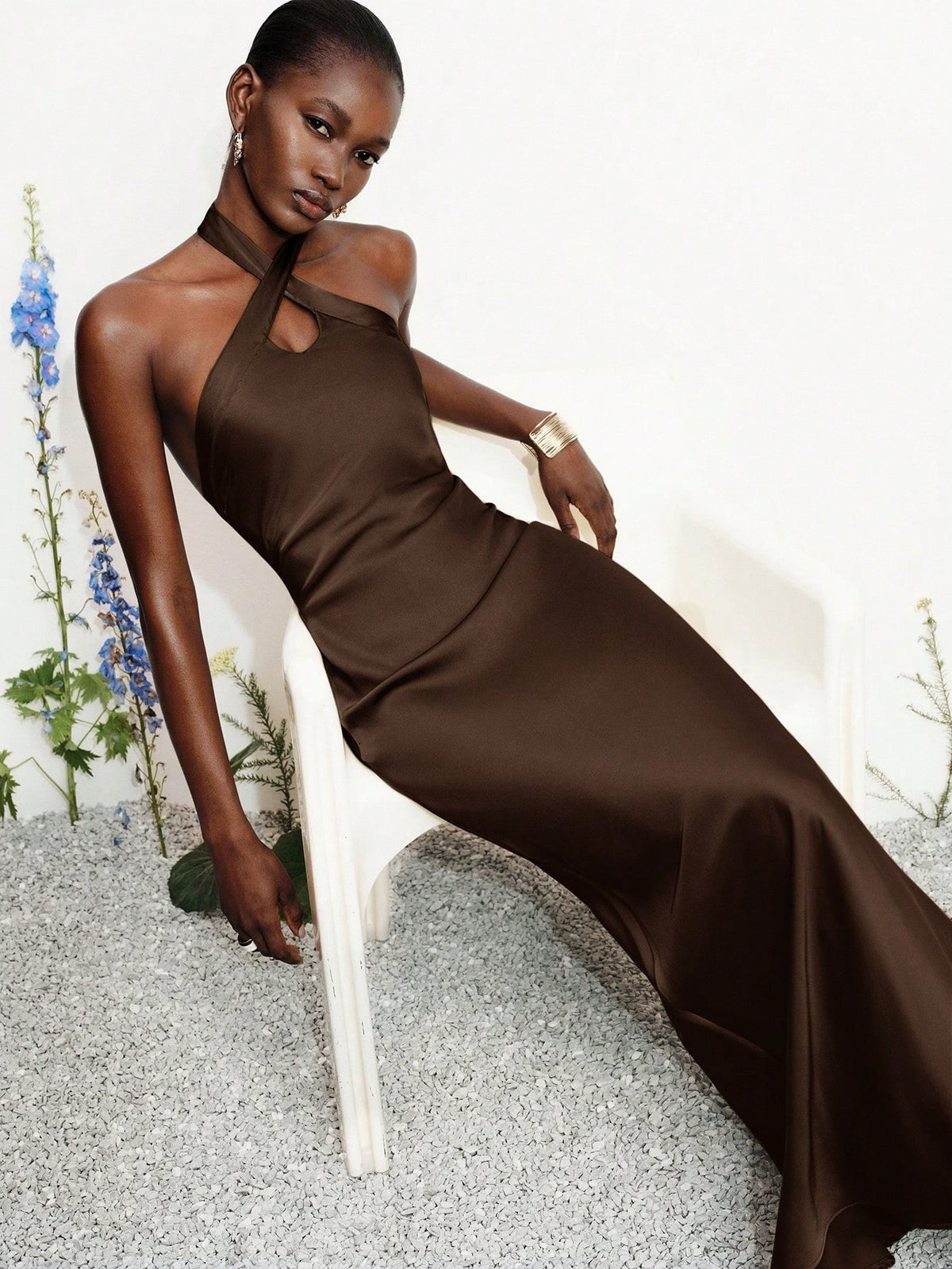 Women's black satin halter neck bodycon midi dress featuring a sleeveless backless design with front slit hem and wrap details.