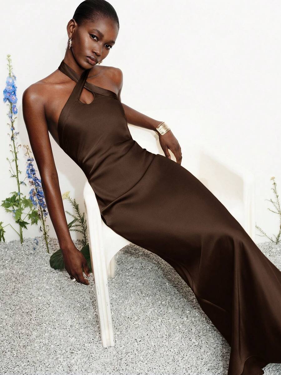 Women's black satin halter neck bodycon midi dress featuring a sleeveless backless design with front slit hem and wrap details.