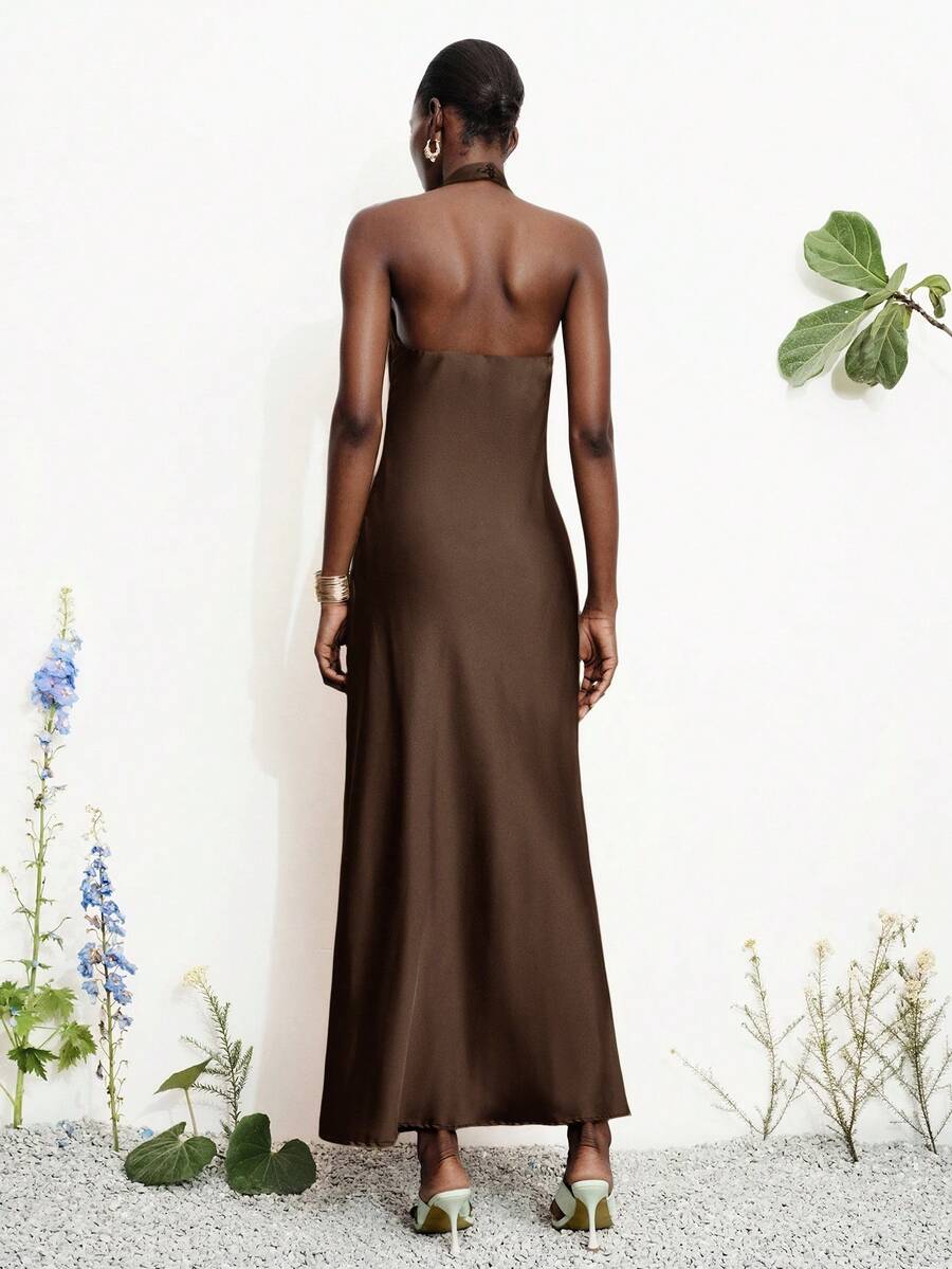 Women's black satin halter neck bodycon midi dress featuring a sleeveless backless design with front slit hem and wrap details.
