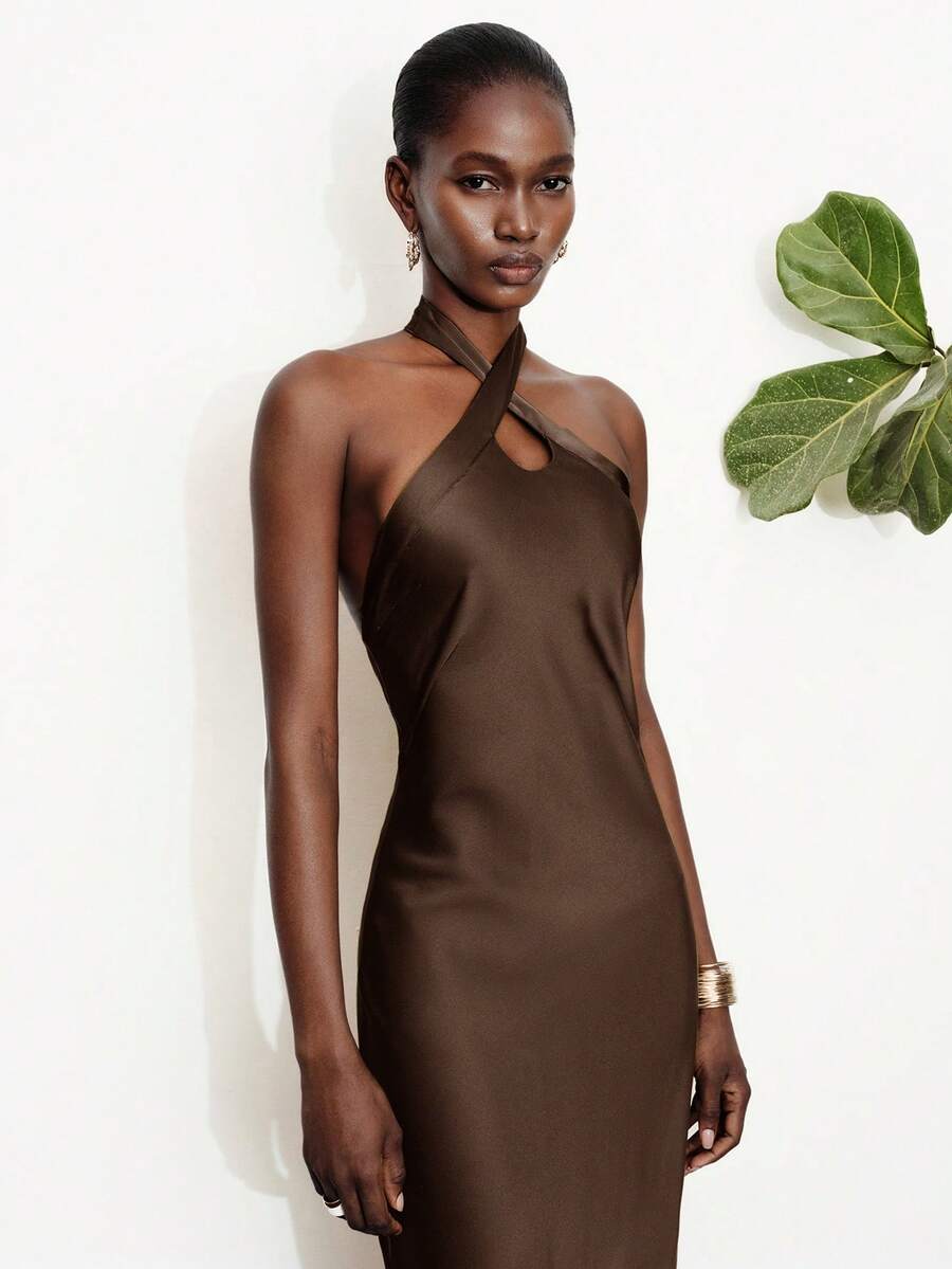 Women's black satin halter neck bodycon midi dress featuring a sleeveless backless design with front slit hem and wrap details.
